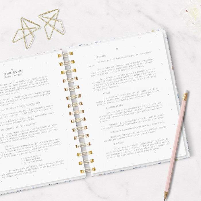 Cuaderno Mi Bullet Journal A5 abierto sobre superficie de mármol con lápiz y clips dorados, mostrando páginas punteadas y anillas doradas.