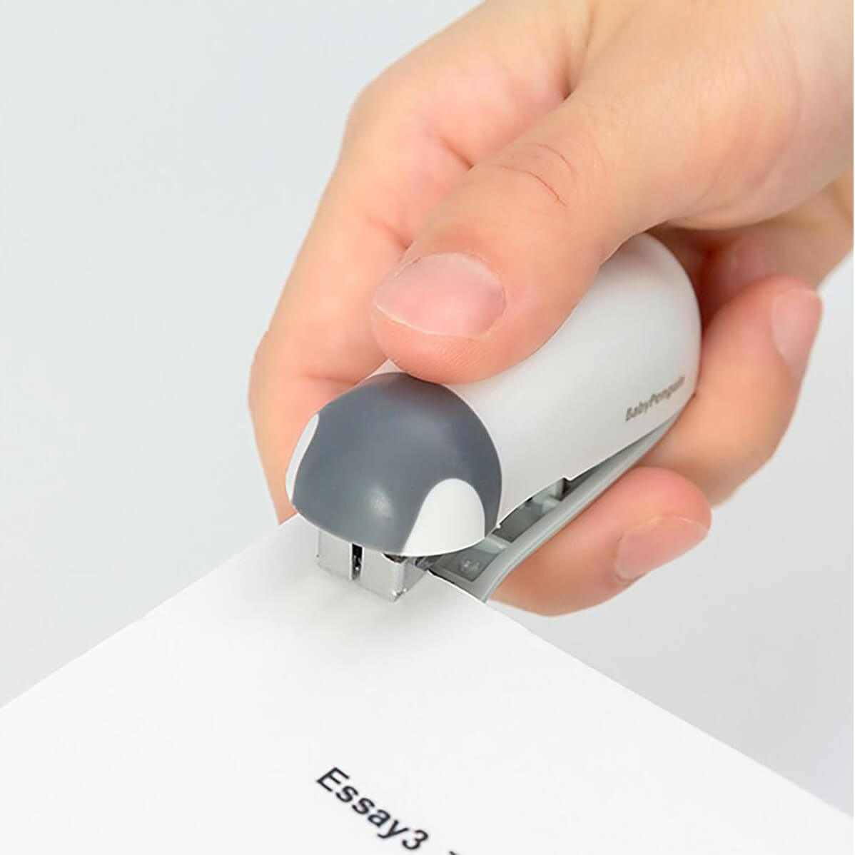 Grapadora Baby Penguin compacta en uso, diseño ergonómico y adorable para oficina.