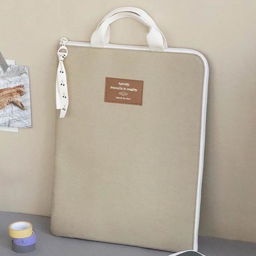 Funda para portátil beige acolchada con asa, diseño versátil de Iconic para proteger dispositivos.