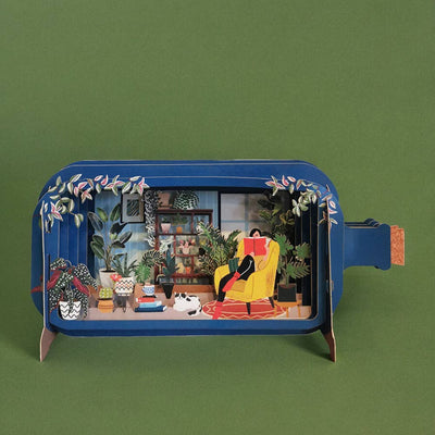 Tarjeta pop-up Plants Reading de Alljoy Design con una chica leyendo entre plantas y un gato