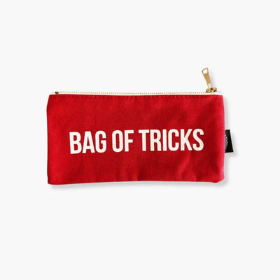 Estuche Canvas Bag of Tricks rojo con texto blanco y cierre dorado.