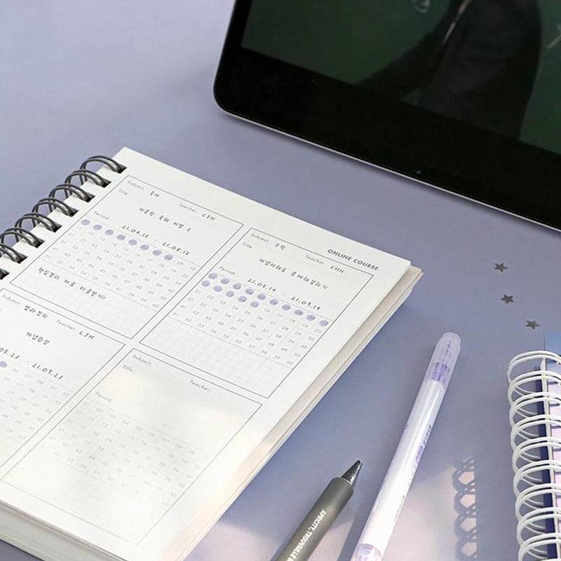 Planificador de Estudios ICONIC HeyDay en uso sobre escritorio, con diseño de anillas y tapa dura, ideal para organización de proyectos.