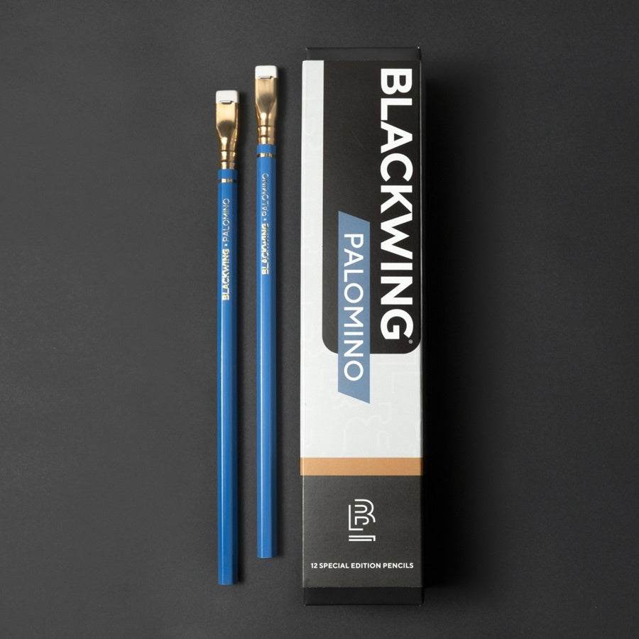 Lápiz BLACKWING Palomino Blue edición limitada con acabado azul, mina de grafito extra firme, férula dorada y goma blanca, junto a su caja.
