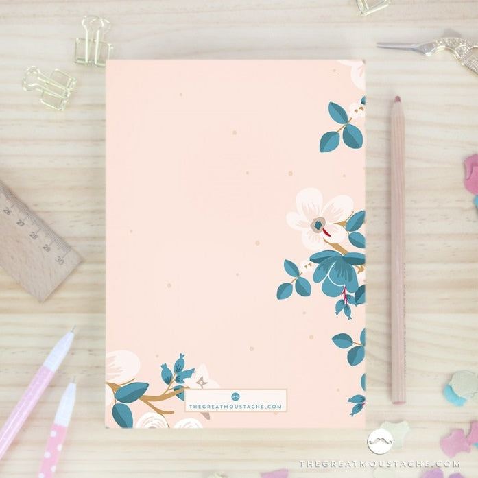 Libreta Grandes Ideas con diseño floral sobre mesa de madera.