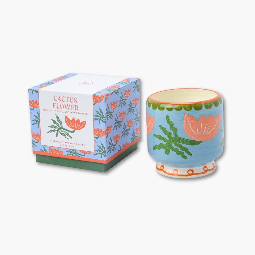 vela perfumada en recipiente de cerámica pintada junto con su caja de cartón de paddywax con dibujo de flores