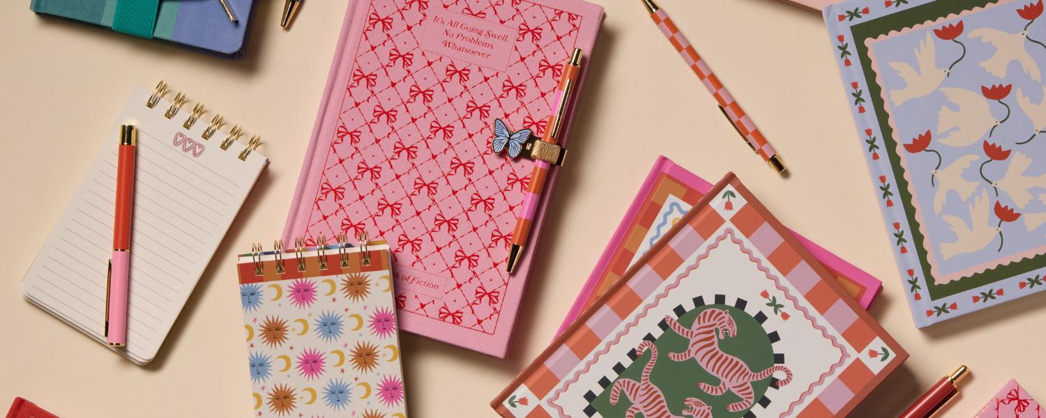 cuadernos, bloc de notas y boligrafos coloridos sobre mesa