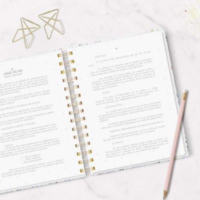 Cuaderno Mi Bullet Journal A5 abierto sobre superficie de mármol con lápiz y clips dorados, mostrando páginas punteadas y anillas doradas.