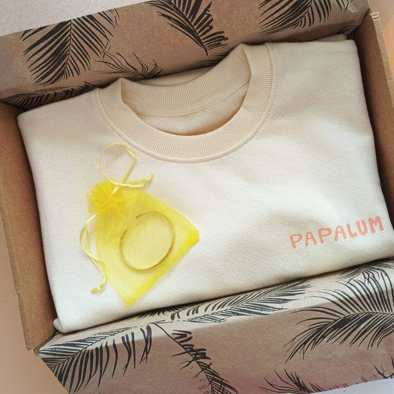Pack de regalo con sudadera y brazalete artesanal "Surf Like a Girl" en caja decorada, ideal para amantes del surf.