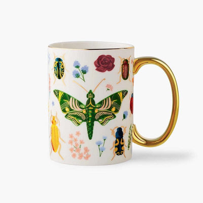 Taza de porcelana Curio Rifle Paper Co. con ilustraciones de insectos y flores, asa dorada.