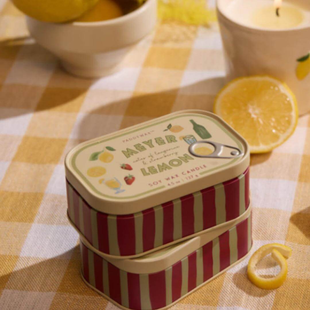 2 latas con velas en su interior sobre una mesa con limones